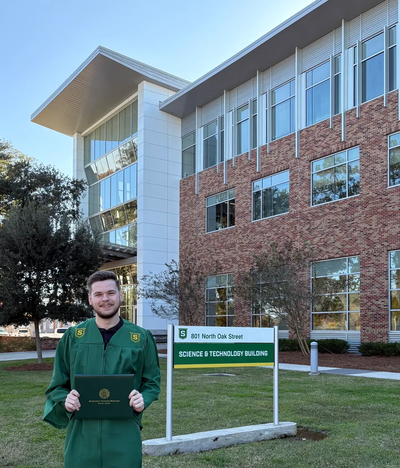 Kade in graduation regalia outside Southeastern Louisiana University’s Science & Technology Building